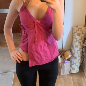 Rosa linne med knytning - Säljer ett rosa linne med knytning framtill. Linnet har en v-ringad design och ärmlös stil. 