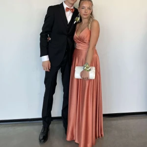 Balklänning rosa/orange - Säljer nu min extremt fina balklänning! Använd en gång, därav nyskick. Fluga och näsduk tillkommer i samma tyg!👗Köpt för 4000kr, kom med bud!! Med tanke på snörning i ryggen så är den lätt att justera med bland annat storlek! Har du fler frågor, skicka dm🤩