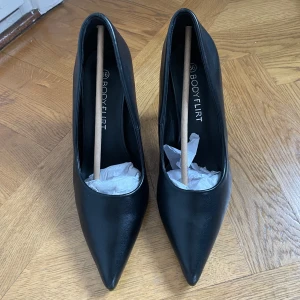 Svarta pumps från Bodyflirt - Eleganta svarta pumps från Bodyflirt med spetsig tå och hög klack. Perfekta för en stilren look. Aldrig använda