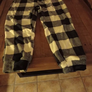 Svart och vit rutiga byxor+tröja  - Nyinköpta mjukisbyxor+tröja.Samma mjuka material på insidan.Tror att det är en normal xl.Byxorna har inga fickor. Dressen är endast provade. 