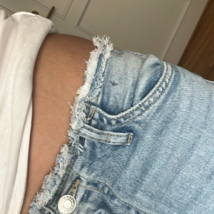 Ljusblå jeans med utsvängda ben från H&M - Snygga ljusblå jeans från H&M med flared leg och justerbar midja. De har en fransig kant upptill och klassisk femficksdesign. Perfekta för en avslappnad stil.