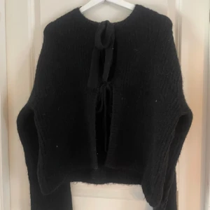 Svart stickad tröja från Gina Tricot - Säljer en svart stickad tröja från Gina Tricot. Tröjan har långa ärmar och en knytning framtill som ger en unik look. Perfekt för kyligare dagar och kan enkelt matchas med olika outfits. Nu utan prislapp men inga defekter💘💘