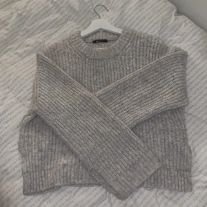 Grå stickad tröja till vårvädret  - Mysig grå stickad tröja med ribbad struktur. Perfekt för kyliga dagar 😍 Tröjan har långa ärmar och en rund halsringning. Har en lite slitts i ärmarna och på sidorna för en lyxigare känsla ✨ (säljer pga att jag har liknande tröjor redan ❤️)