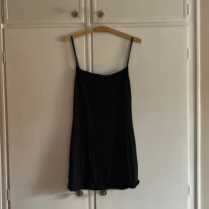 Svart klänning - Säljer en stilren svart klänning med smala axelband. Perfekt för en minimalistisk look. Klänningen har en enkel och elegant design som passar till många tillfällen.