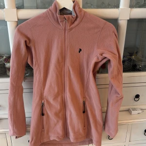 Rosa fleecejacka från Peak Performance - Säljer en rosa fleecejacka från Peak Performance. Jackan har dragkedja framtill och två praktiska fickor med dragkedjor. Perfekt för kyliga dagar och ger en mysig känsla. 💖