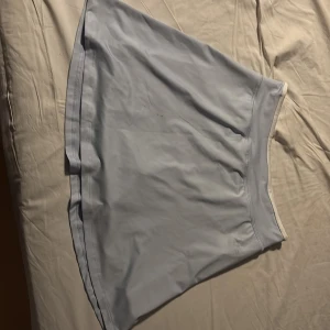 Ljusblå tenniskjol från H&M Move - Säljer en ljusblå tennis kjol med lite diskreta inbyggda shorts från H&M Move. Kjolen har en enkel design med en elastisk midja för bekväm passform. Perfekt för en avslappnad stil.