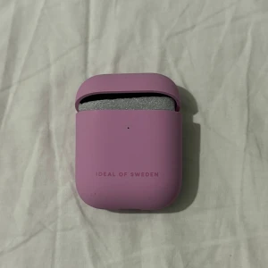 Rosa AirPods 1/2-fodral från Ideal of Sweden - Säljer ett snyggt rosa AirPods 1/2-fodral från Ideal of Sweden. Fodralet har en stilren design och skyddar dina AirPods med stil. Perfekt för att ge dina hörlurar en personlig touch!