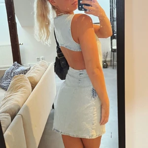 Ljusblå jeansklänning med öppen rygg - Snygg ljusblå klänning i denim med en snygg öppen ryggdesign. Dragkedja i sidan. Endast använd en gång. 