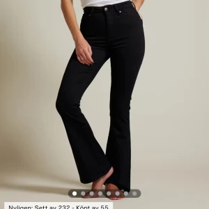 Svarta Peachy Flare jeans - Snygga svarta Peachy Flare jeans med hög midja och utsvängda ben. Perfekta för en trendig look. De har en klassisk femficksdesign och är tillverkade i ett bekvämt material som ger en smickrande passform. Helt nya med prislapp kvar