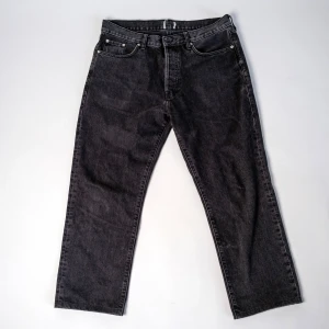 Svarta jeansbyxor - Svarta second hand-jeans Säljer ett par snygga svarta jeans med knappgylf i bra skick. Perfekt för dig som vill ha en tidlös och lättmatchad byxa! Byxorna är second hand som vi har fräschat upp och säljer för ett billigare pris! 📏 Storlek: W32, L32📌 Skick: Bra skick 💡 Passform: Baggy 