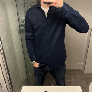 Mörkblå skjorta - ✅Snygg mörkblå skjorta med knappar och långärmad design. Perfekt för en stilren look. Passar bra till både jeans och mer formella byxor.✅ 99kr