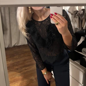 Svart spetsblus från Zara - Säljer en elegant svart spetsblus från Zara med långa ärmar och vackra spetsdetaljer. Blusen har en croppad passform och är perfekt för en stilfull look. Den är tillverkad i ett fint spetsmaterial som ger en lyxig känsla. Storlek L