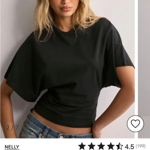 Svart kortärmad topp från Nelly - Snygg svart topp från Nelly med korta ärmar och en avslappnad passform. Perfekt för en stilren look. Tillverkad i ett mjukt material som känns skönt mot huden.
