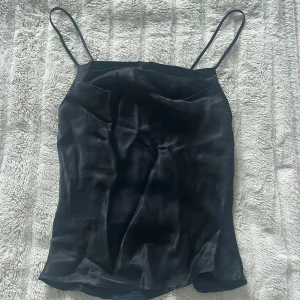 Svart satinlinne - Svart linne i satin med tunna axelband i strl XS. Säljer för 79kr