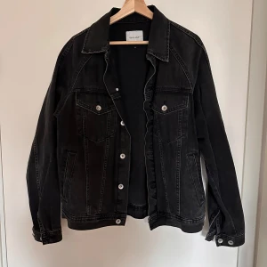 Svart jeansjacka från Vailent - Snygg svart jeansjacka från Vailent (Carlings) med klassisk design. Jackan har knappar framtill och två bröstfickor med knappstängning. Perfekt för en avslappnad stil.