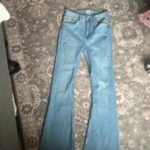 Ljusblå bootcut jeans - Snygga ljusblå bootcut jeans från 157. De har en klassisk femficksdesign och en sliten look med små revor. Perfekta för en avslappnad stil.