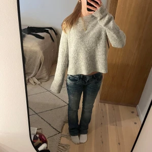 Grå stickad tröja - Säljer en mysig grå stickad tröja med långa ärmar. Tröjan har en croppad passform och är perfekt för kyligare dagar. Den är enkel och stilren, vilket gör den lätt att matcha med olika outfits. Nästan aldrig använd och är i super skick! Skriv för eventuella frågor💕