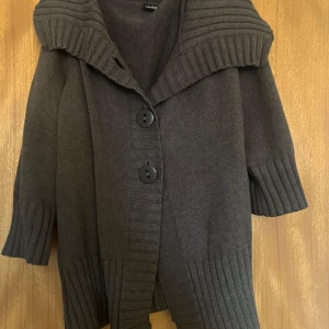 Brun stickad kofta med stora knappar - Mysig brun stickad kofta med stora knappar framtill. Den har en bred krage och trekvartsärmar med ribbade muddar. Perfekt för kyliga dagar. Stolek XXL men passar mig som är S/M