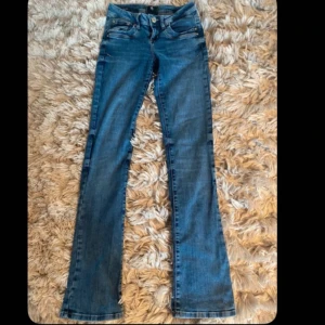 Blå jeans ltb  - Snygga blå jeans från Ltb med en klassisk design. De har en bootcut-stil och är utrustade med både knappar och dragkedja. Perfekta för en avslappnad look. Modellen är Valerie💕 storlek 24x34