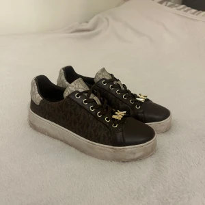 Michel Kors skor  - Bruna Michel Kors sneakers i storlek 38, säljer då dom känns förstora så 39 skulle nog även passa. Använda fåtal gånger.  Har ett slitage på ena skon då mk-märket på skon är i metall och slitigt litegrann.  Köpta för 800kr och säljer för 450kr