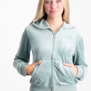 Juicy Couture - Säljer en supermjuk och skön ljusblå Juicy Couture velour hoodie med dragkedja framtill. Den har en broderad logga på bröstet och en praktisk huva. Perfekt för mysiga dagar eller en avslappnad stil. Passar bra till både höst och vår!