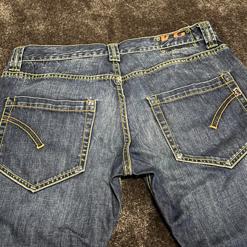 Säljer ett par snygga blå jeans från Dondup. De har en klassisk femficksdesign med gul kontrastsöm som ger en cool look. Jeansen är i bra skick och har en knappgylf. Perfekta för vardagsbruk eller en avslappnad utekväll!. Jeans & Byxor.