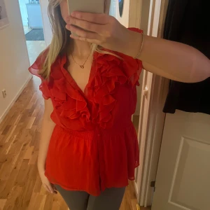 Röd blus med volangdetaljer - Säljer en superfin röd blus med volangdetaljer framtill!!❤️Skulle säga att den passar M/L 😍