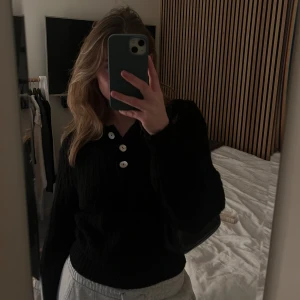 Stickad tröja med krage - Supersnygg svart stickad tröja med krage och 3st knappar som snygga detaljer. Knappt använd, i väldigt fint skick.