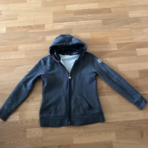 Grå moncler cardigan/tröja - Säljer denna då den var alldeles för liten, det är storlek S men passar folk som har xxs-xs passar mig i armarna men är väldigt kort annars. Skick 9-10 Priset ej hugget i sten🙌 Hör av er om mer frågor!