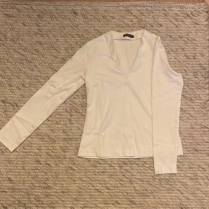 Vit långärmad topp från 3.1 Phillip Lim - Säljer en stilren vit långärmad topp från Stockholm. Den har en v-ringad design och är perfekt för både vardag och fest. Materialet känns mjukt och bekvämt mot huden. Passar bra till både jeans och kjol! Har själv använt den under kavaj. 
