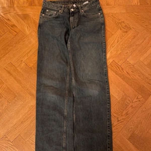 Weekday jeans modell arrow Mörkblå  - Snygga mörkblå jeansbyxor med klassisk femficksdesign och en rak passform. Byxorna har en hög midja och är perfekta för en avslappnad stil. De är tillverkade i slitstarkt denim och har en knappgylf.