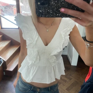 Vit topp med volanger - Säljer en söt vit topp med volanger och v-ringning💕