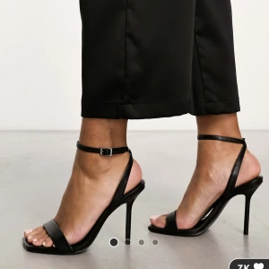 Svarta sandaler med klack från ASOS DESIGN - Snygga svarta sandaler med klack från ASOS DESIGN. De har en elegant design med smala remmar och en fyrkantig tå. Perfekta för att ge en stilren touch till din outfit. Säljs pga för liten storlek aldrig använda. Uk 5 motsvarar 38