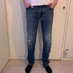 Blå jeans från Jacob Cohen - Vi säljer ett par riktigt snygga jeans från Jacob Cohen i blå färg. Jeansen har en slitning på främre knä vilket är en del av designen. Modellen är 184 cm och väger 69 kg. Jeansen modell är slim till straight