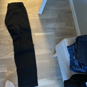 Svarta jeansbyxor från Lindex - Säljer ett par svarta jeansbyxor från Lindex. De har en klassisk design med knappar och dragkedja framtill. Perfekta för en stilren look.
