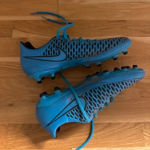 Fotbollsskor Nike - Snygga blå fotbollsskor från Nike med ett unikt nätmönster och klassisk snörning. Perfekta för fotbollsplanen med sin stilrena design och funktionalitet. Storlek 44