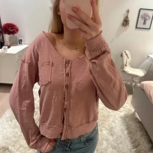Rosa blus med knappar - Säljer en söt rosa blus med knappar framtill och en liten bröstficka. Koftan har långa ärmar och en avslappnad passform.