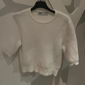 Vit stickad topp Zara - Fin vit tröja från Zara med korta ärmar och rund hals. Toppen har en fin stickad textur. Säljs pga att den är för liten.