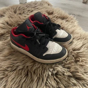 Nike Air Jordans i svart och rött och vitt - Snygga Nike Air Jordans i svart och rött med klassisk design. Skorna har en röd Nike-logga på sidan och Air Jordan-logga på hälen. Perfekta för dig som älskar stil och komfort.