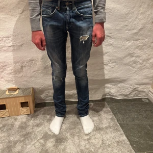 Blå Dondup jeans - Säljer ett par riktigt feta Dondup jeans med en sliten design och en tight passform. Byxorna har en klassisk femficksdesign och är perfekta för en avslappnad stil. Killen på bilden är 170cm! Var inte rädd för att höra av div vid några frågor eller funderingar!😉🤩