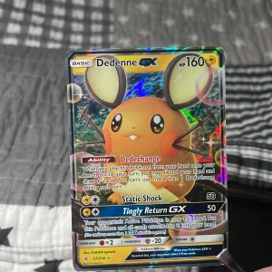 Dedenne GX Pokémonkort - Säljer ett Dedenne GX Pokémonkort med 160 HP. Kortet har förmågan Dedechange och attacker som Static Shock och Tingly Return GX. Det är en del av serien 57/214 och har en holografisk yta som ger det en cool glans. Perfekt för samlare eller spelare som vill stärka sin kortlek! Obs igen frakt!