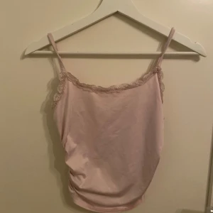 Rosa linne från Shein - Söt rosa linne från Shein med spetsdetaljer längs kanterna. Linnet har smala axelband och en mjuk, glansig yta som ger en elegant touch. Perfekt för varma dagar eller som ett lager under en tröja.