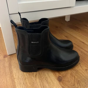 GANT Rubbersy gummistövlar, 36 - Stilrena svarta gummistövlar från GANT, ”Rubbersy rubber boot”, i storlek 36, Perfekt för regniga dagar eller en promenad i stan. Stilrena och bekväma. Skorna är i mycket fint skick då knappt använda.