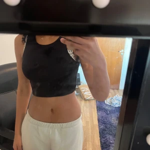 Svart ribbad linnetopp - Snygg svart ribbad linnetopp från Stradivarius. Perfekt för en stilren look med sin ärmlösa design och croppade passform. Enkelt att matcha med olika outfits. Säljer lika i grön!