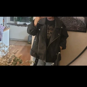 Svart skinnjacka med dragkedjor - Cool svart skinnjacka med dragkedjor och en avslappnad passform. Perfekt för en edgy look. Jackan har långa ärmar och en klassisk bikerstil. Oanvänd, oversize modell. Storlek s. 