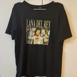 Svart t-shirt med Lana Del Rey-tryck - Snygg svart t-shirt med ett stort tryck av Lana Del Rey på framsidan. Perfekt för gorgeous lana stans. T-shirten har en normal passform och korta ärmar. Den är i cirka s/m