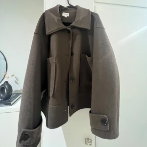 Brun  kappa från Kappahl  - Säljer en stilren brun kappa kappahl med stora fickor och knappar framtill. Jag är 163⭐️