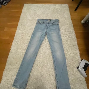 Ljusblå jeans från Polo Ralph Lauren - Snygga ljusblå jeans från Polo Ralph Lauren med klassisk femficksdesign och knappgylf. Perfekta för en avslappnad stil med en touch av elegans.
