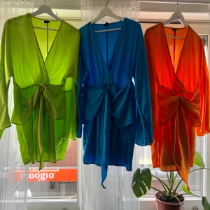 Färgglad omlottklänningar  med knytband - Säljer 3 för 1  snygga korta omlottklänning i tre olika färger: limegrön, blå och orange. Klänningarna  har långa ärmar och ett knytband i midjan som ger en fin siluett. Perfekt för att lysa upp garderoben!