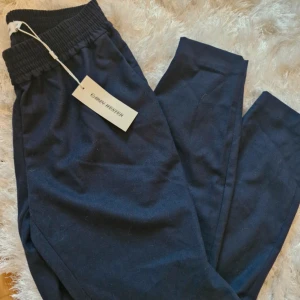 Mörkblå byxor från Carin Wester  - Snygga mörkblåa byxor från Carin Wester med elastisk midja för extra komfort. Tillverkade i en blandning av viskos, polyester och elastan vilket ger en mjuk och stretchig känsla. Perfekta för en stilren look. Som mjukare kostymbyxor i strl 36. Korta i modellen, jag är 1,57 då blir de nästan hellånga men är man längre lär de bli kortare på. ⭐️